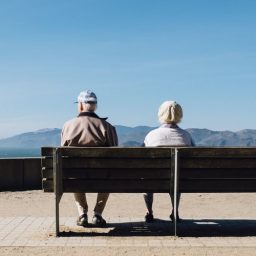 一对老年夫妇坐在长椅在一起。
