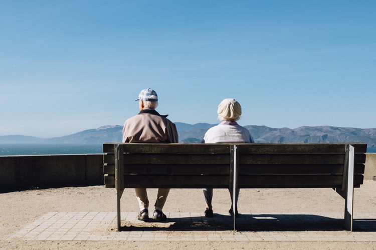 An older couple sits on a bench together.