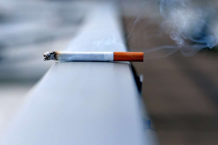 A lit cigarette on a ledge.