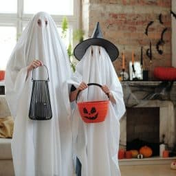 A parent and child dressed up as ghosts for Halloween.